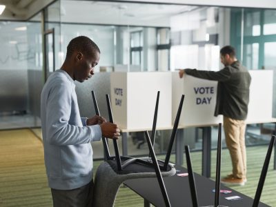 Homens organizam cabines de votação em uma seção eleitoral interna.