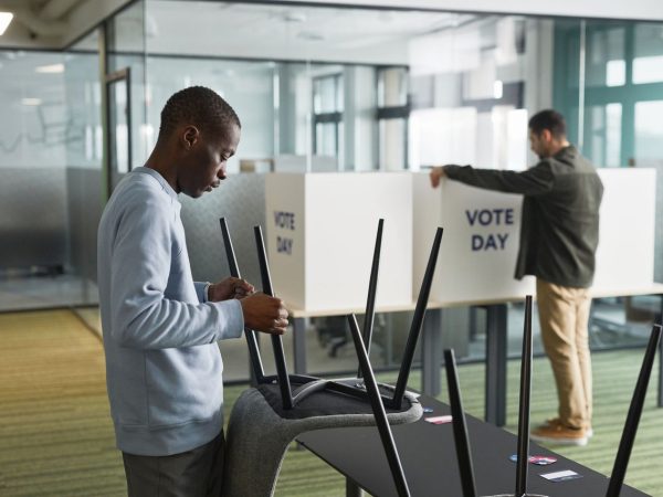 Homens organizam cabines de votação em uma seção eleitoral interna.
