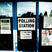 Entrada de um local de votação, com portas e identificação da seção eleitoral.