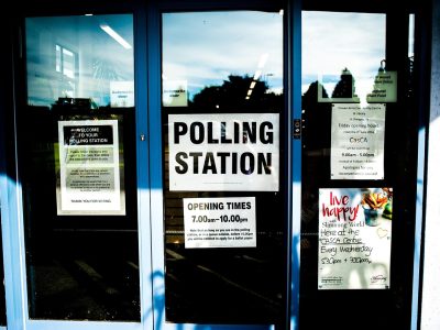 Entrada de um local de votação, com portas e identificação da seção eleitoral.