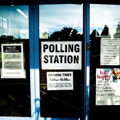 Entrada de um local de votação, com portas e identificação da seção eleitoral.