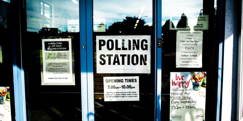 Entrada de um local de votação, com portas e identificação da seção eleitoral.
